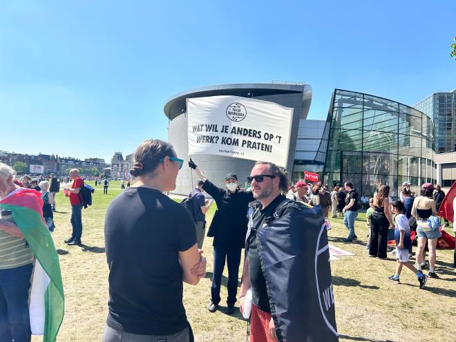 Tech workers talking with each other with a banner in the background
