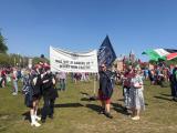 Tech workers stand on a grassy field at Museumplein Amsterdam showing flags for Tech Workers Coalition